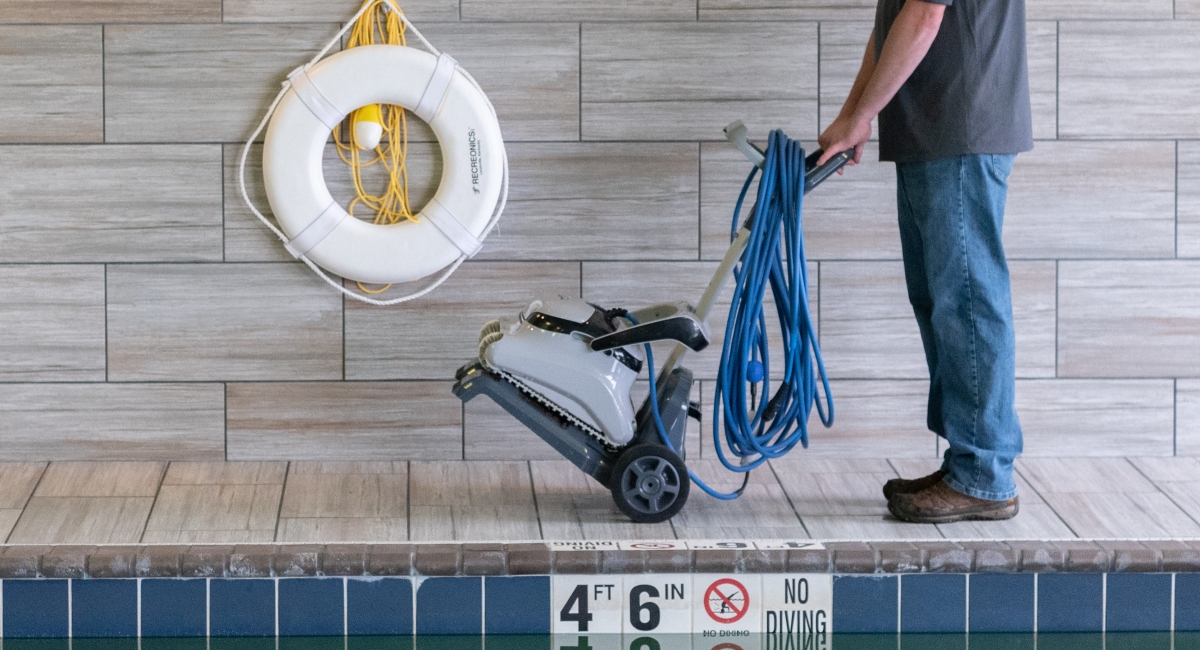A janitor handling a pool cleaning robot.