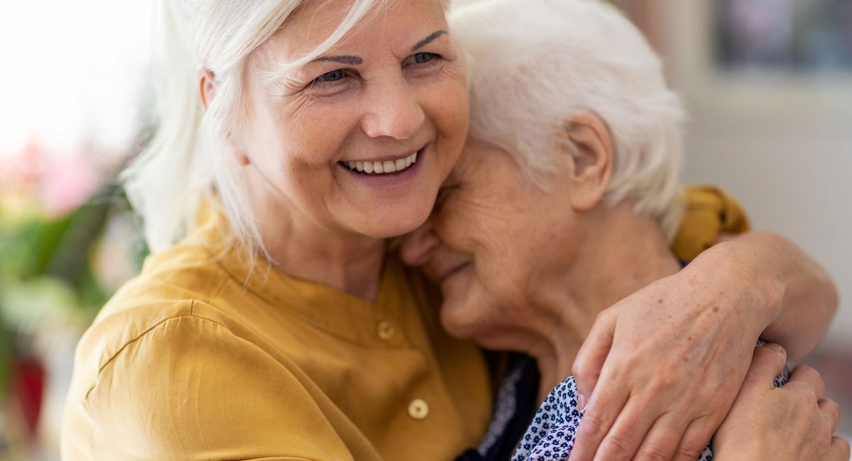 elderly lady being hugged by a woman